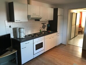 A modern kitchen with white cabinets, a built-in stove, and a coffee maker. - Große Wohnung in Nesse mit Garten und Terrasse by Interhome (Nessmersiel)