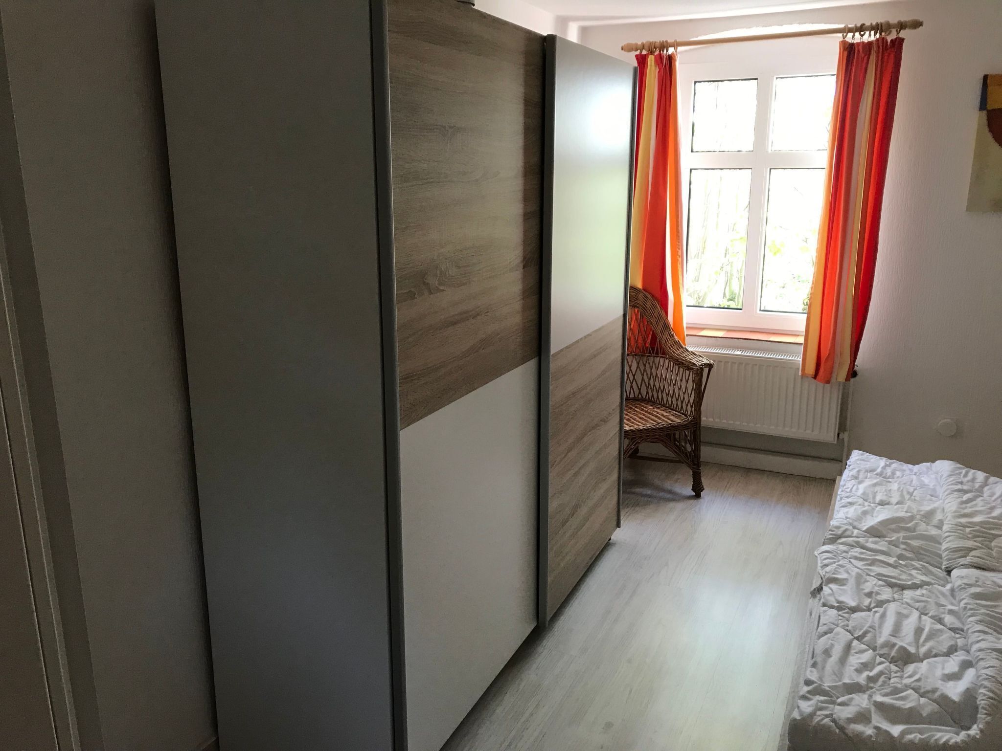 Ein Schlafzimmer mit einem Bett, einem Sessel und einem Fenster mit Vorhängen.
