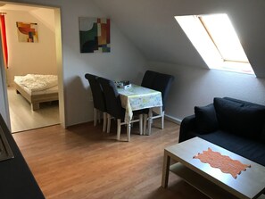 A small, cozy room with a dining table, chairs, a sofa, and a bed. - Große Wohnung in Nesse mit Garten und Terrasse by Interhome (Nessmersiel)
