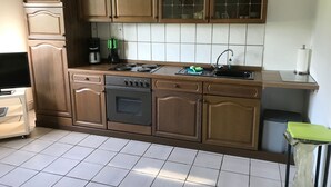 Uma cozinha com armários de madeira, fogão, lava-louças e pia.