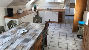 A compact kitchen with white cabinets, a wooden countertop, and a dining table with chairs. - Große Wohnung in Nesse mit Garten und Terrasse by Interhome (Nessmersiel)