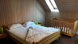 A wooden bed with a white mattress and pillows, a wooden crib, and a skylight above. - Große Wohnung in Nesse mit Garten und Terrasse by Interhome (Nessmersiel)