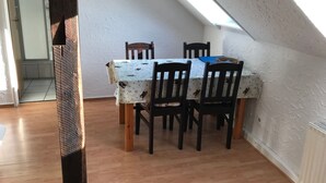 A dining area with a table and chairs, a sloped ceiling, and a view of the adjacent room. - Große Wohnung in Nesse mit Terrasse und Garten by Interhome (Nessmersiel)