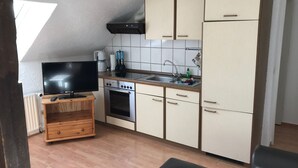 A compact kitchen with a built-in oven, a sink, and a television on a wooden stand. - Große Wohnung in Nesse mit Terrasse und Garten by Interhome (Nessmersiel)