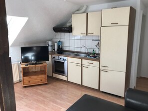 Eine kompakte Küche mit Einbauofen, Spüle und Fernseher auf einem Holzboden.