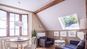 Ein gemütliches Wohnzimmer mit Holzboden, einem Esstisch mit Stühlen, einer Couch und einem kleinen Beistelltisch.