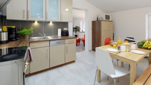 Eine moderne Küche mit Essbereich, ausgestattet mit einer Mikrowelle, einer Kaffeemaschine und einem für das Frühstück gedeckten Esstisch.