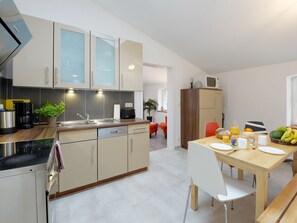 Eine moderne Küche mit Essbereich, ausgestattet mit einer Mikrowelle, einer Kaffeemaschine und einem für das Frühstück gedeckten Esstisch.