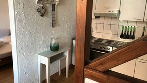 Eine Küche mit Herd, einem kleinen Tisch und einem Regal mit Küchenutensilien.