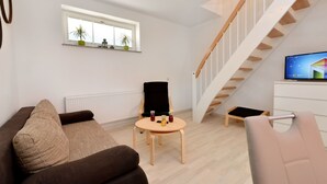 A modern living room with a sofa, a small table, a chair, a TV, and a staircase. - Moderne Wohnungen in historischem Ambiente unweit zur Altstadt und zum Hafen by Interhome (Stralsund)