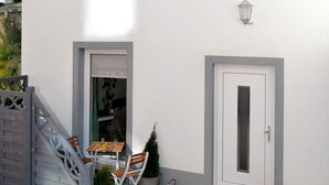 A two-story building with a white exterior, a small window, and a door. There is a wooden staircase leading to a door with a small table and chairs outside. - Moderne Wohnungen in historischem Ambiente unweit zur Altstadt und zum Hafen by Interhome (Stralsund)