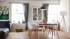A modern living room with a dining area, wooden flooring, and a large window with curtains. - Hochwertige, helle FeWo mit Meerblick am Deich by Interhome (Nessmersiel)