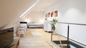 A modern bedroom with a sloped ceiling, a bed, a dresser, a TV, and artwork on the wall. - Hochwertige, helle FeWo mit Meerblick am Deich by Interhome (Nessmersiel)