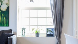 A room with a window, a hanging star ornament, a potted plant, a green basket, and a white chair. - Hochwertige, helle FeWo mit Meerblick am Deich by Interhome (Nessmersiel)