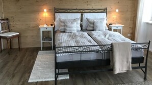 A bedroom with a wooden wall, a metal bed frame, two bedside tables, and a window. - Kräuterhof-Ferienwohnung by Interhome (Missen-Wilhams)