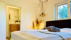 Une chambre à coucher avec un lit, une fenêtre et une salle de bain visible au fond.