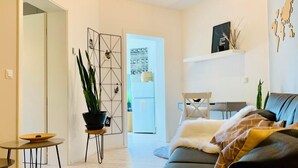 Un salon moderne avec un canapé, une petite table, une plante en pot et un élément décoratif mural.