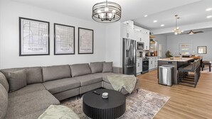 Una sala de estar moderna con un sofá modular, una mesa de centro negra y una cocina al fondo.