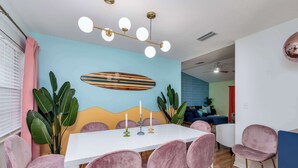 Un comedor con una mesa blanca, sillas rosas y una lámpara de techo.