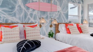 Habitación de hotel con cama, cabecera, ventana y pared con un diseño abstracto azul y blanco.
