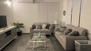 A modern living room with a sofa, coffee table, and TV stand. - Palmas y Brisas – Comfortable 2-Bedroom Home Near the Beach (Barceloneta)