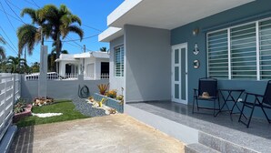 A modern house with a patio area, a white fence, and a small garden with plants and a pathway. - Palmas y Brisas – Comfortable 2-Bedroom Home Near the Beach (Barceloneta)