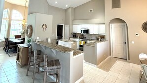 A spacious kitchen with a central island, built-in appliances, and a dining area with chairs and a table. - Luxury Waterfront Home-Heated Pool-Dock-Sleeps 10 (Cape Coral)
