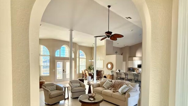A spacious living room with a high ceiling, a ceiling fan, and a view into the kitchen area. - Luxury Waterfront Home-Heated Pool-Dock-Sleeps 10 (Cape Coral)