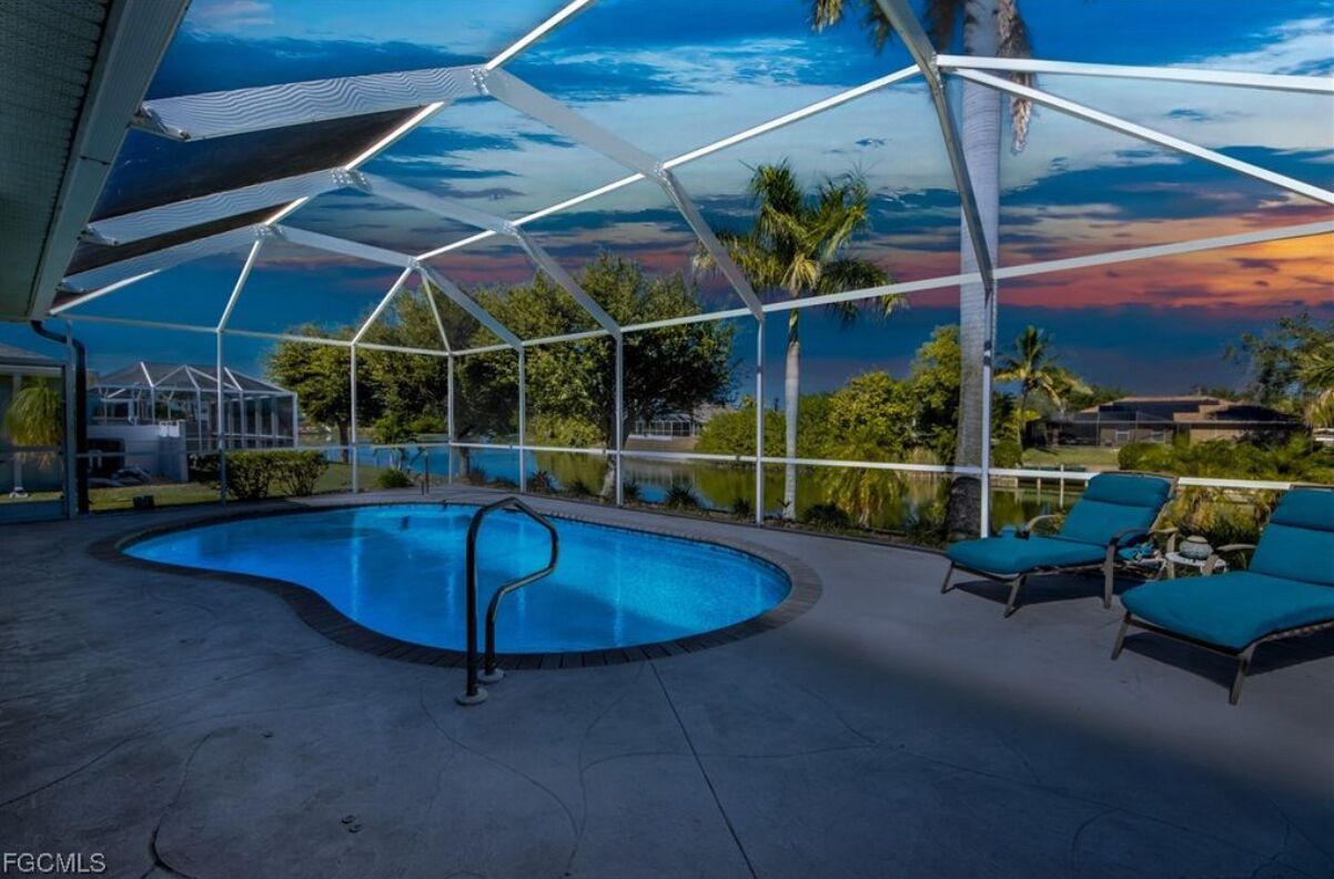 Una piscina con vista a palmeras y al atardecer.