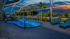 A swimming pool with a view of palm trees and a sunset. - Luxury Waterfront Home-Heated Pool-Dock-Sleeps 10 (Cape Coral)