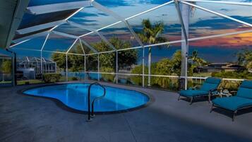 Una piscina con vista a palmeras y al atardecer.