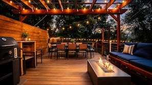 An outdoor patio with wooden flooring, a barbecue grill, a fire pit, a wooden table, and a blue sofa. - 2 Homes, 8BR | Sleeps 30 | Game Room & Fire Pit (Denver)