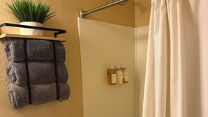 A bathroom with a toilet, a shower, and a towel rack with a plant. - Welcoming studio with AC in charming Goodyear (Goodyear)