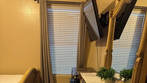 A bedroom with a bed, a dresser, a mirror, and a window with blinds. - Welcoming studio with AC in charming Goodyear (Goodyear)