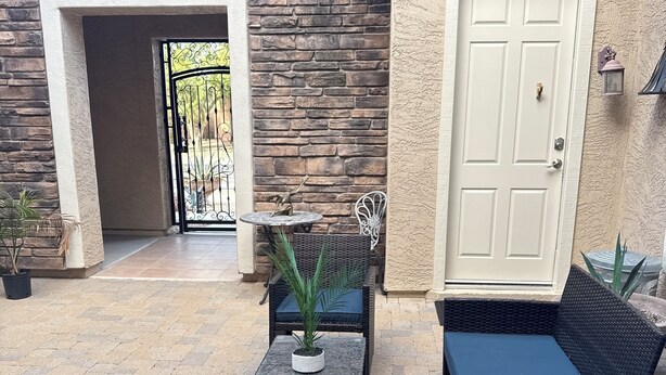 An outdoor patio area with wicker furniture, a small table with a potted plant, and a door with a mailbox. - Welcoming studio with AC in charming Goodyear (Goodyear)
