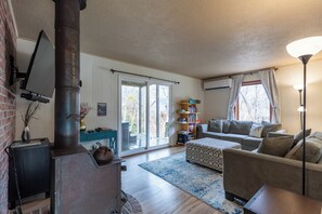 A living room with a fireplace, a sofa, a coffee table, and a bookshelf. - Ski, Hike, and Relax by the Creek - Hot Tub, Creek Access, Sleeps 11 (Banner Elk)