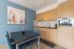 Una cocina moderna con armarios de madera, horno integrado y comedor con mesa y sillas.