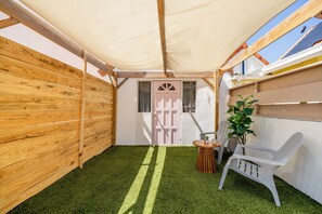 A wooden deck with a white chair and a small table, a potted plant, and a door with a window. - Central Cozy Apartment • 7 Min to Palm Beach (Noord)