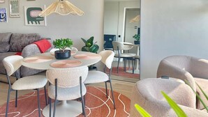 A modern living room with a round dining table, chairs, a sofa, and a large mirror.
