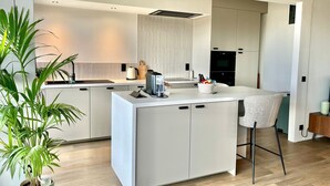 A modern kitchen with a central island, white cabinetry, and a bar stool.