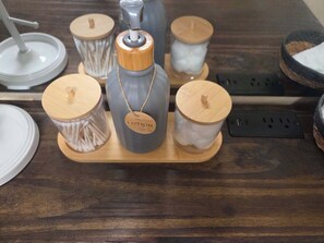A wooden tray with three containers, one with a metal lid and a tag labeled "LOTION," and two with wooden lids.