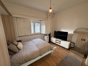 A bedroom with a bed, a TV, a wardrobe, and a window. - Ground Floor Studio for 2 PAX (Lisbon)
