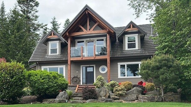 Une maison à deux étages avec un porche à l’avant, un garage et une pelouse bien entretenue.