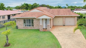 A two-story house with a red-tiled roof, a front garage, and a well-maintained lawn. - Your Pet Friendly Home Away From Home In Yeppoon | Sleeps 10 (Yeppoon)