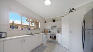 A modern kitchen with white cabinets, a built-in oven, and a refrigerator. - Your Pet Friendly Home Away From Home In Yeppoon | Sleeps 10 (Yeppoon)
