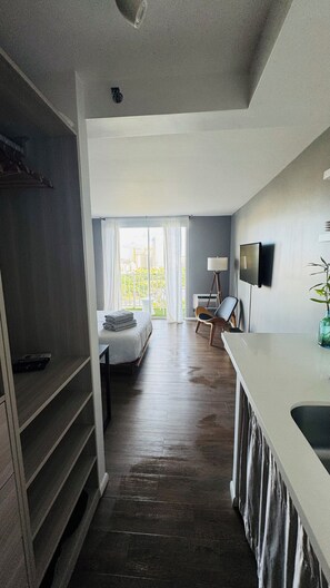 A modern hotel room with a large bed, a desk, and a view of the city through the balcony. - Modern Studio Waikiki Beach (Honolulu)
