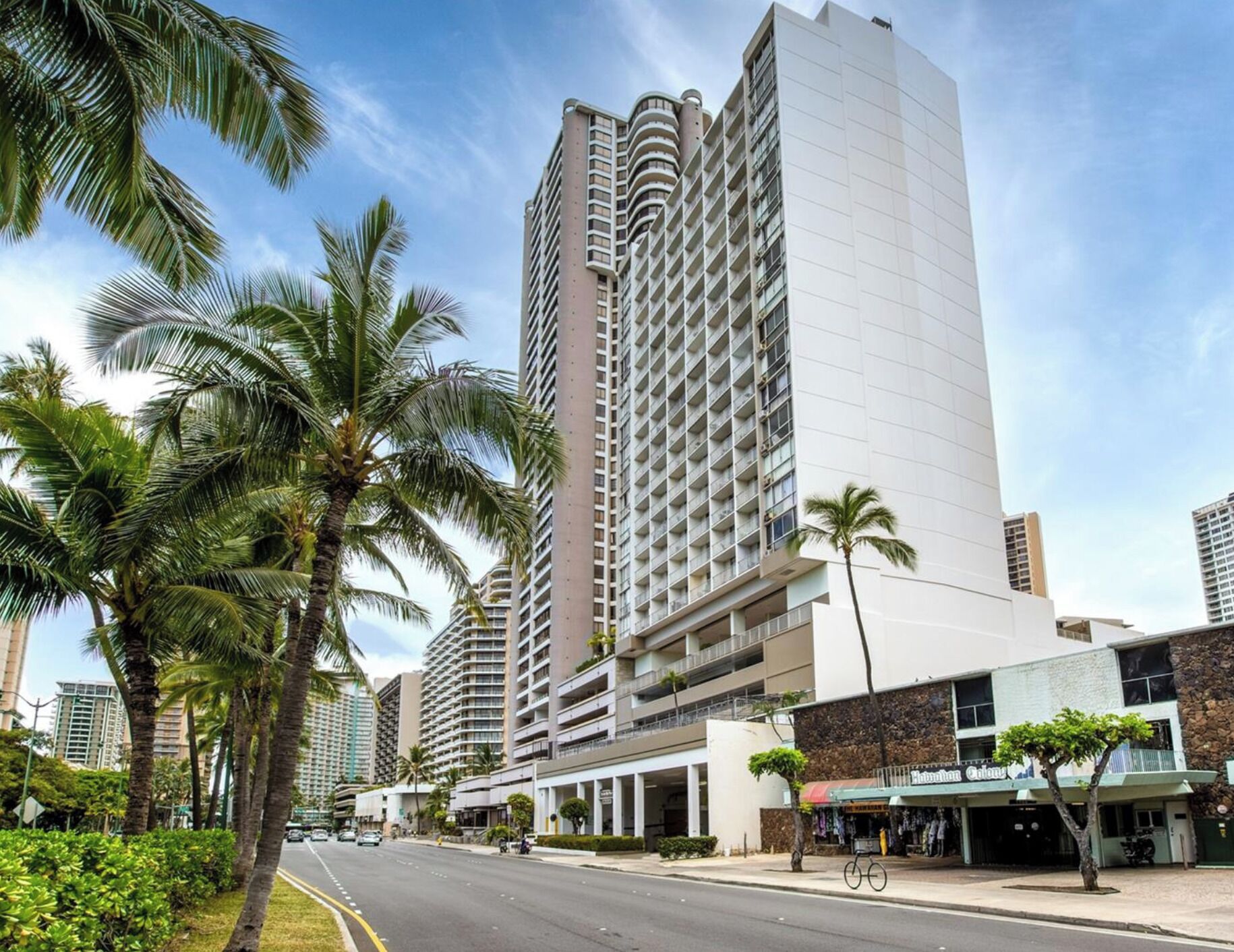 A high-rise hotel with multiple floors, a central courtyard, and palm trees.