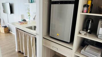 Eine moderne Küche mit einem eingebauten, Edelstahl-Kühlschrank, Holzschränken und einem flachbildfernseher an der Wand.