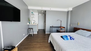 Una habitación de hotel moderna con cama, escritorio, silla, televisor y baño.