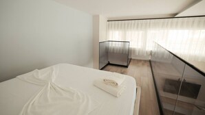 A modern hotel room with a large bed, a glass balcony, and a view of the city. - Duplex City 01 in Durr s (Durrës)